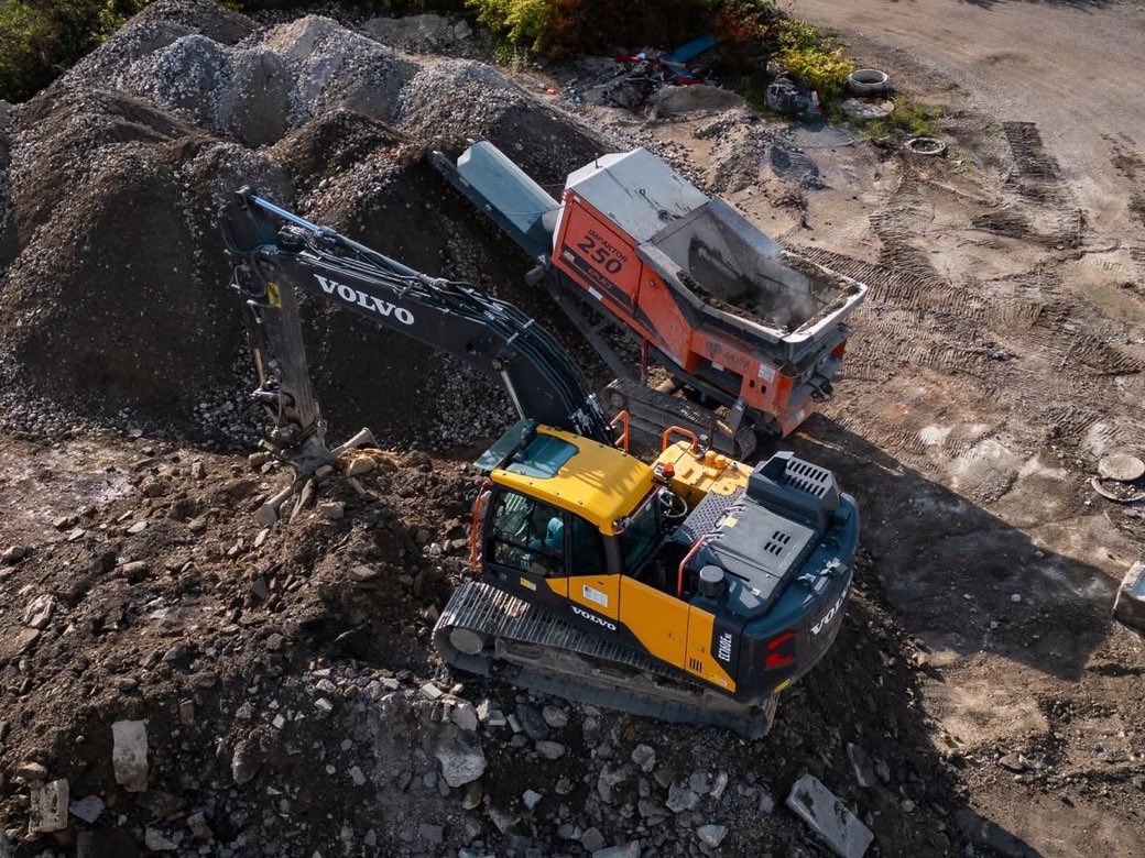 Vue aérienne par drone d'un chantier de terrassement : pelle sur chenilles et concasseur en action